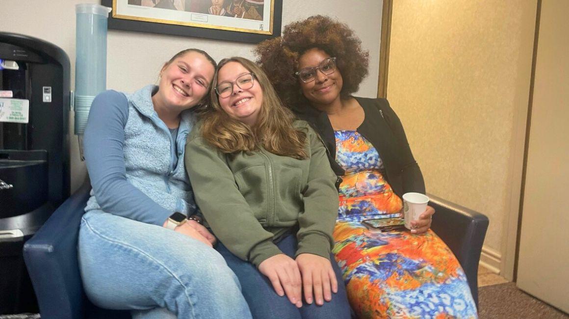 Three girls sit together on a couch during bible study.