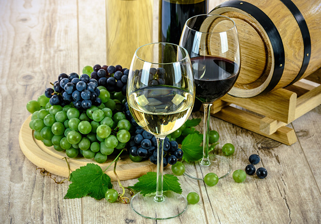 Wine glasses with grapes on a wine barrel