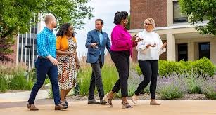 Five people professionally dressed walking and talking outside of an office building